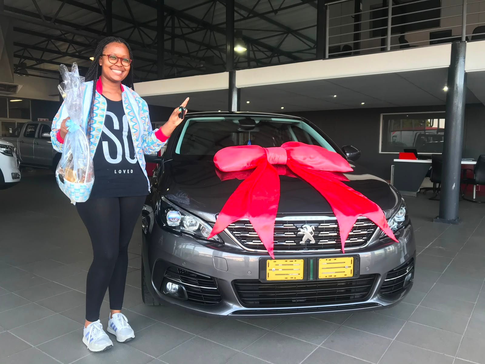 Client beside a black vehicle with a red bow
